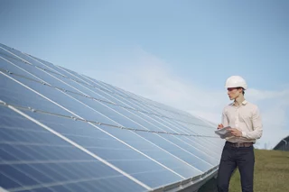 Techniker mit Schutzhelm prüft eine Solaranlage